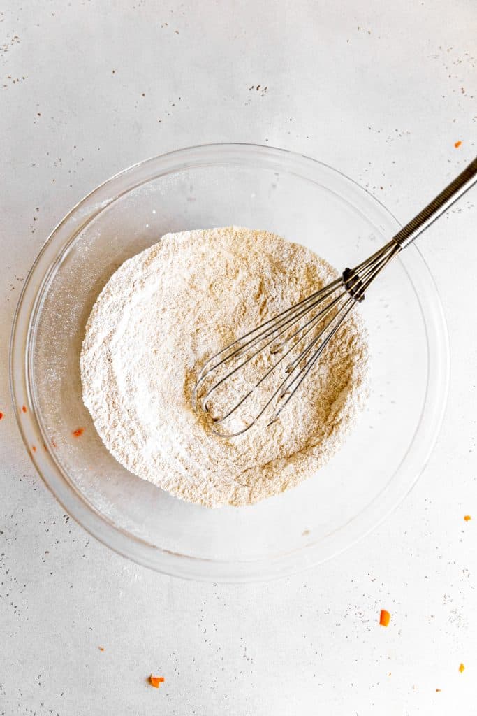 Glass bowl of whisked together dry ingredients for carrot cake batter.