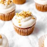 Carrot cake cupcake topped with chopped walnuts.