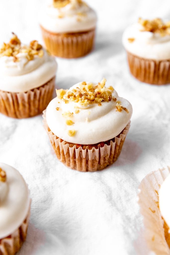 Carrot cake cupcake topped with chopped walnuts.