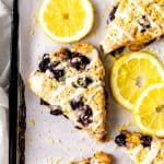 Lemon blueberry scones on a baking sheet with lemon slices and a linen napkin.