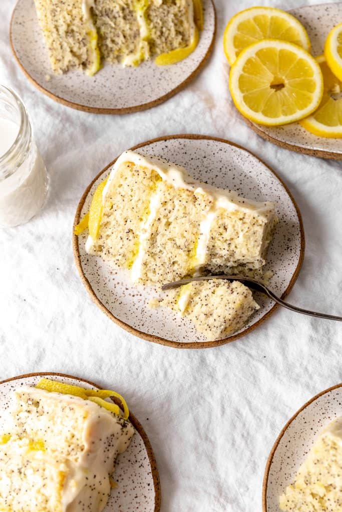 Fork cutting into a slice of vegan lemon poppyseed layer cake.