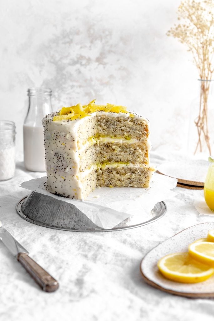 Lemon poppyseed layer cake that is missing a few slices.