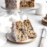 Slice of Oreo cake on a plate next to a knife covered in frosting.