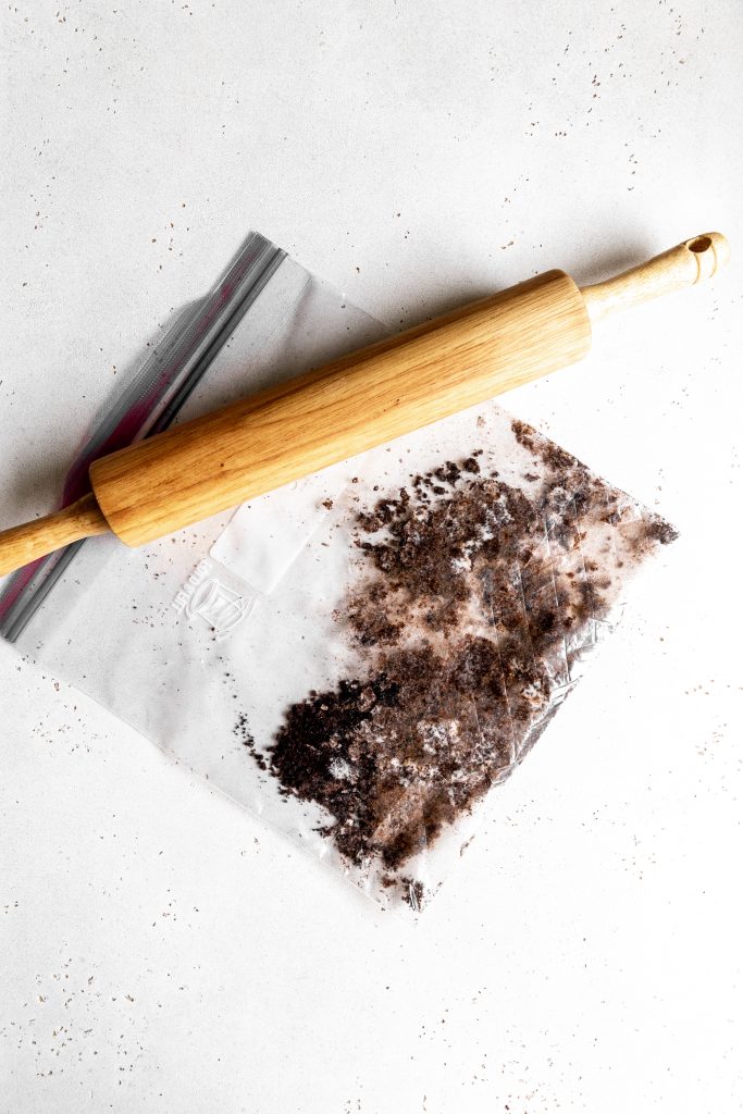 A rolling pin and a plastic bag filled with crushed Oreos.