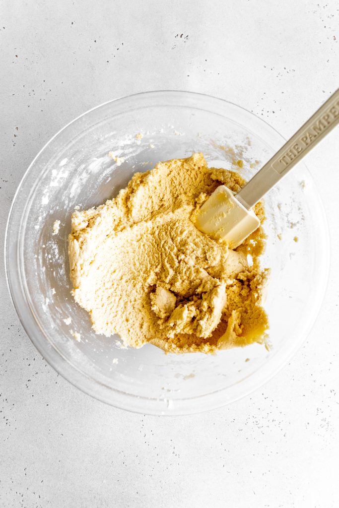 Cookie crust dough in a glass bowl with a rubber spatula.