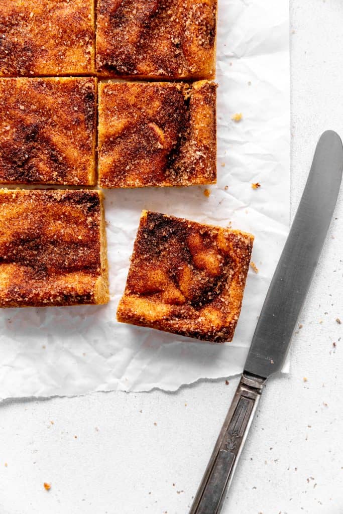 Vegan snickerdoodle bar and a knife on parchment paper.