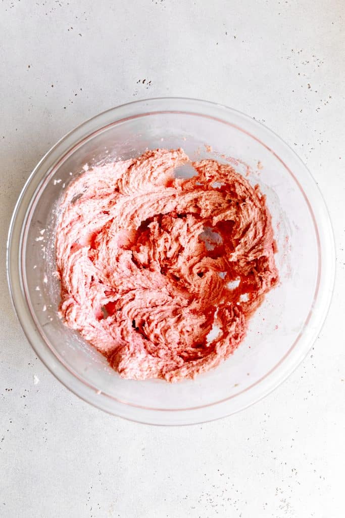 Creamed vegan butter, sugar and strawberry powder in a glass bowl.