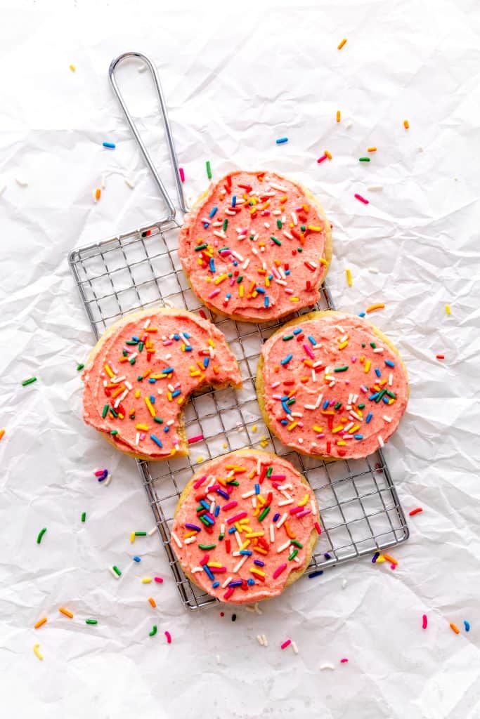 Frosted vegan sugar cookies on a wire cooling rack on a white background.