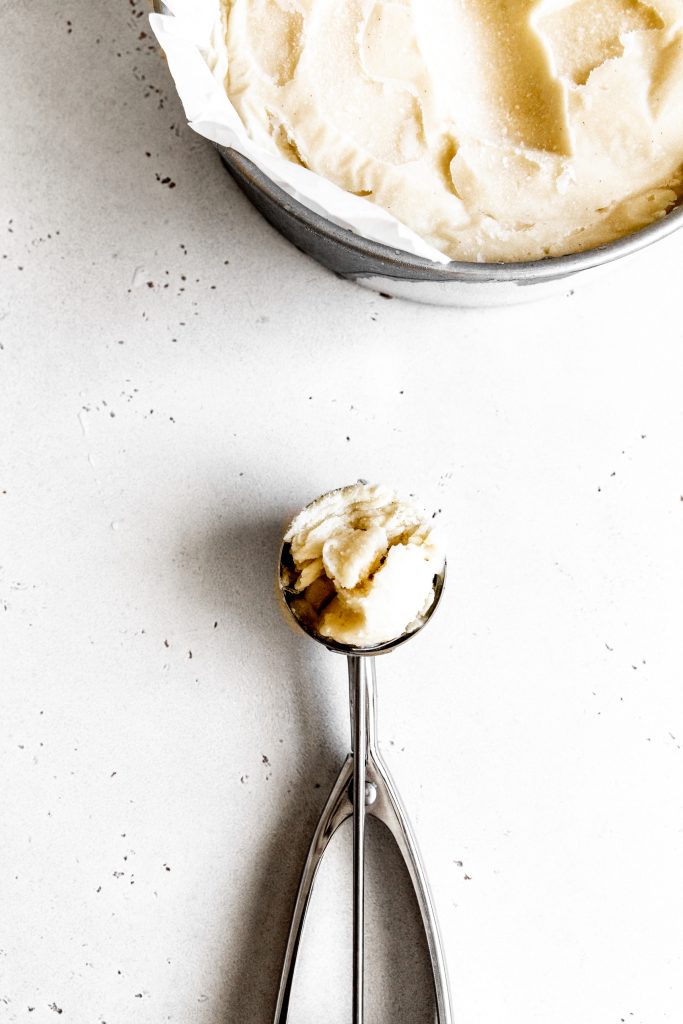 Silver ice cream scoop filled with vanilla ice cream.