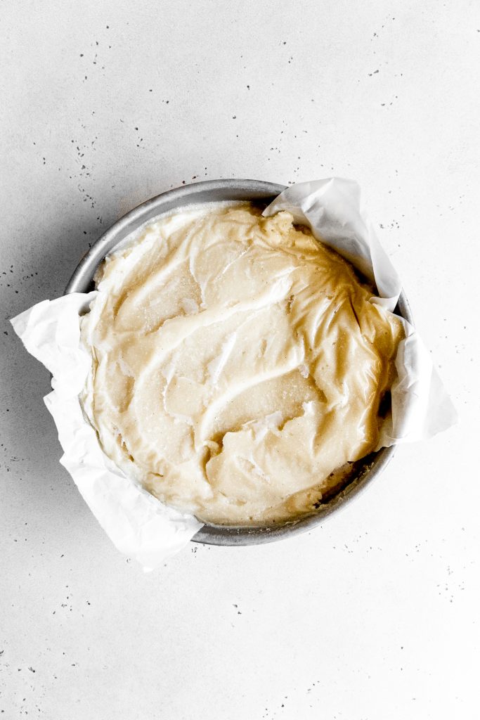 Frozen vanilla ice cream in a round cake pan lined with parchment paper.