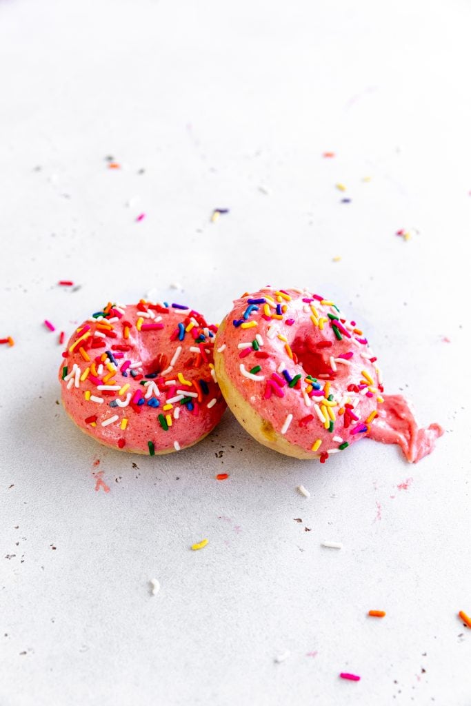 Baked, frosted donut propped against another donut.