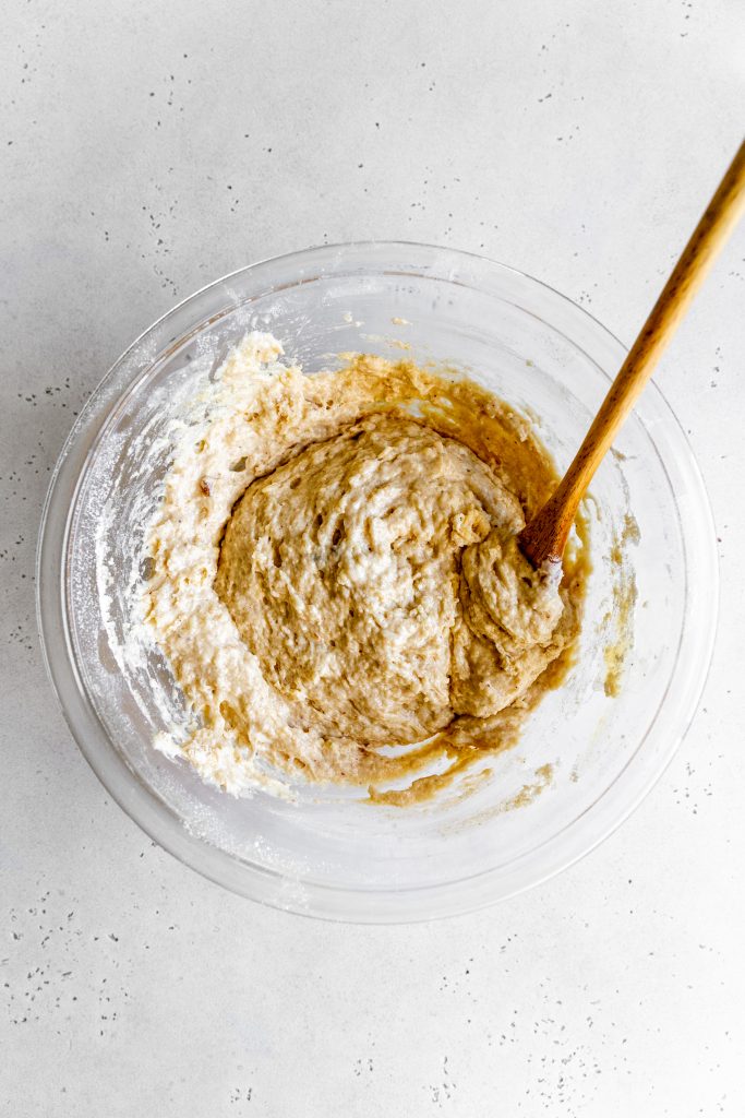 Glass bowl filled with vegan baked donut batter with a wooden spoon.