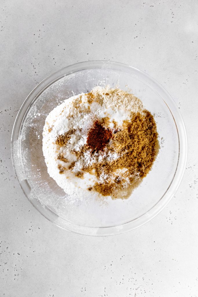 Glass bowl filled with the dry ingredients needed for baked donuts.