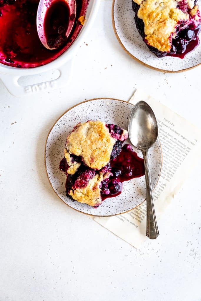 Blackberry cobbler on a white plate with a spoon.