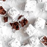 Brownie bite broken in half on a baking sheet with more brownie bites.