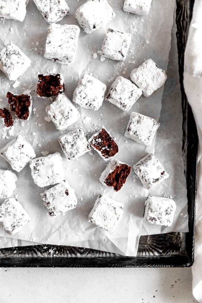 Brownie bites coated in powdered sugar on a baking sheet.