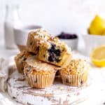 Lemon blueberry muffin with a bite taken out of it on top of more muffins.