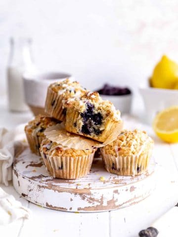 Lemon blueberry muffin with a bite taken out of it on top of more muffins.