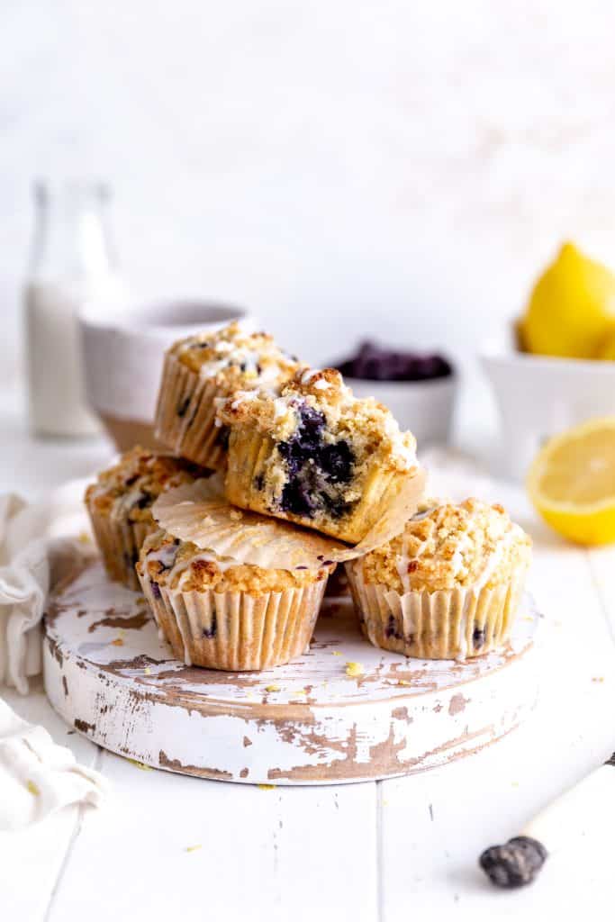 Lemon blueberry muffin with a bite taken out of it on top of more muffins.