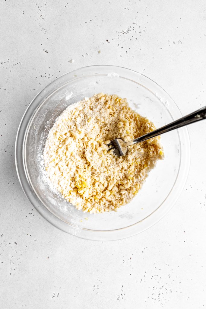 Glass bowl filled with dry streusel topping and a fork.