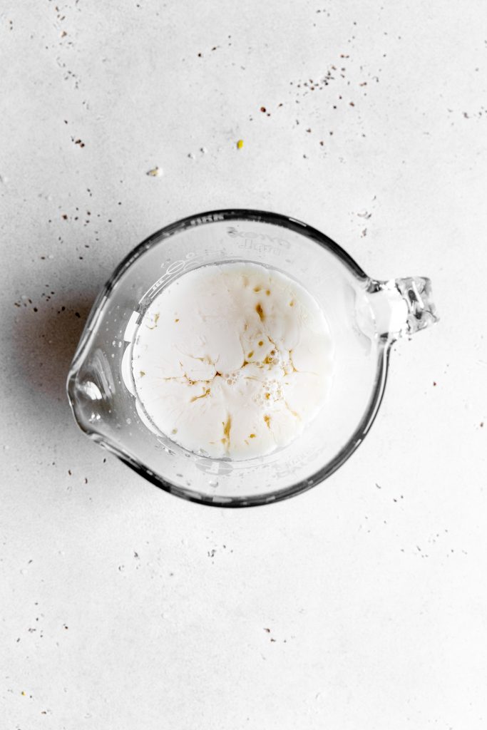 Glass measuring cup filled with milk and lemon juice.