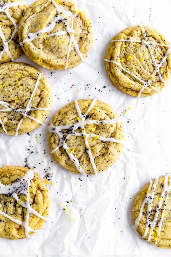 Lemon poppy seed cookies on parchment paper sprinkled with poppy seeds and lemon zest.