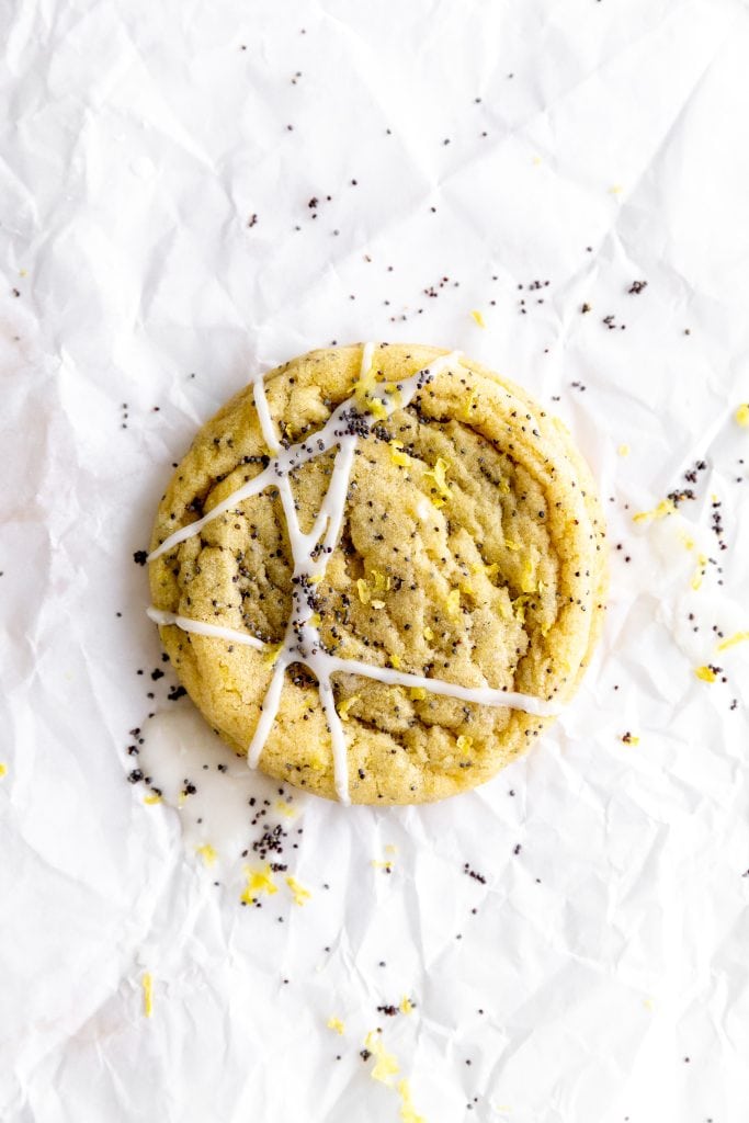 Lemon poppy seed cookie drizzled with lemon glaze on parchment paper.