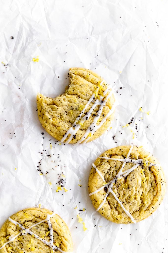 Lemon poppyseed cookie with a bite taken out of it on parchment paper.