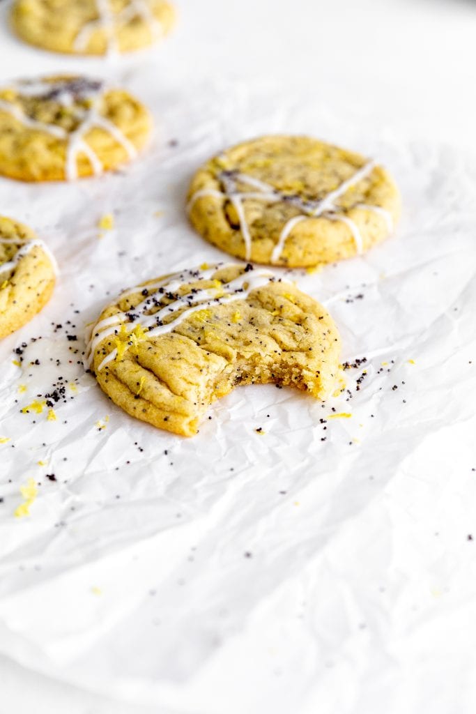 Lemon poppyseed cookie with a bite taken out of it on parchment paper.