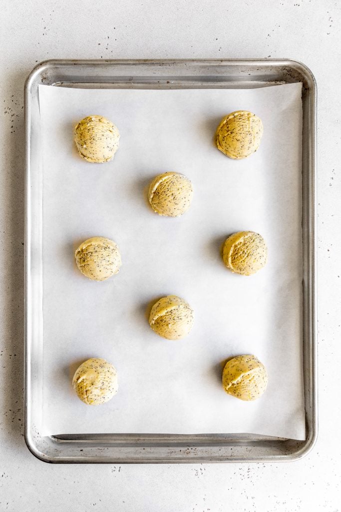 Unbaked lemon poppy seed cookies on a baking sheet.