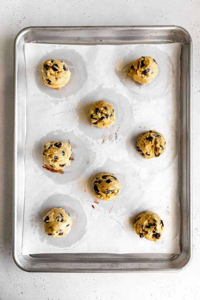 Unbaked orange chocolate chip cookies on a baking sheet.