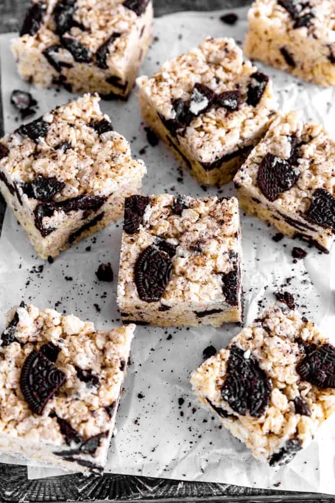 Oreo rice krispie treats on parchment paper surrounded by broken cookie pieces.