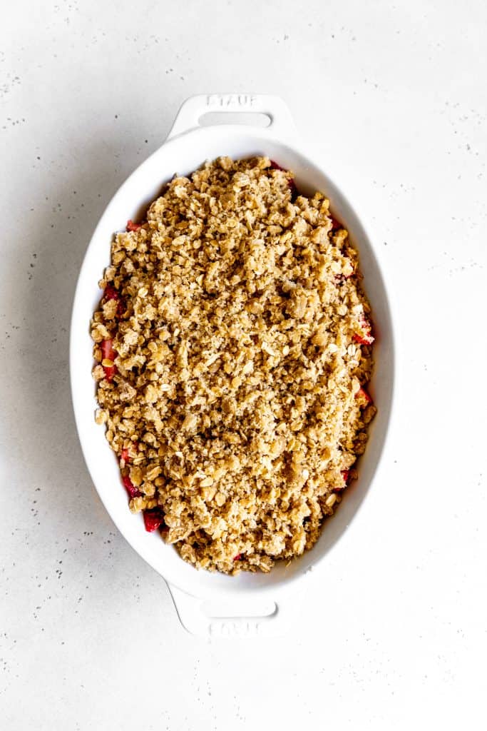 Unbaked strawberry crisp in a white baking dish.