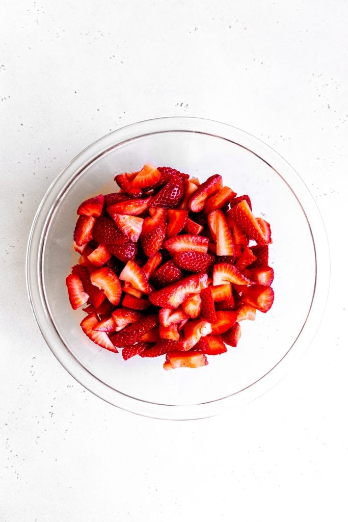 Glass bowl filled with sliced strawberries.