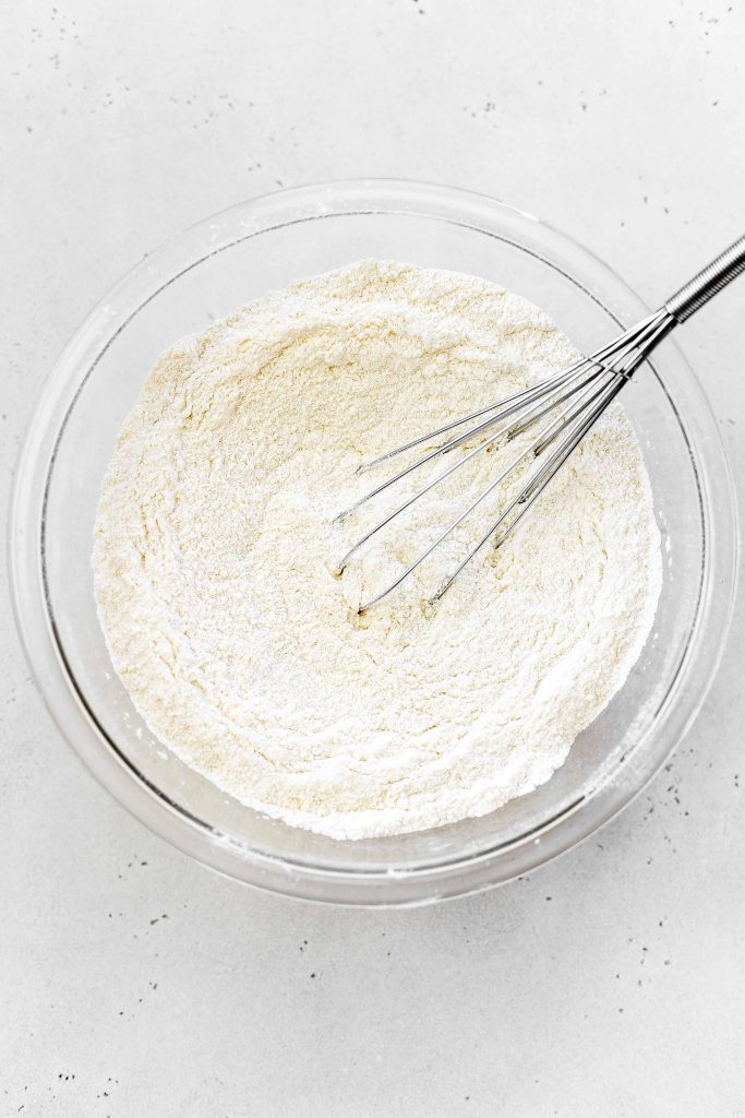 Dry cake ingredients in a glass bowl with a wire whisk.