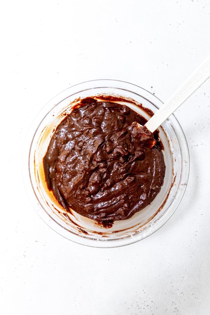 Glass bowl filled with brownie batter and a rubber spatula.