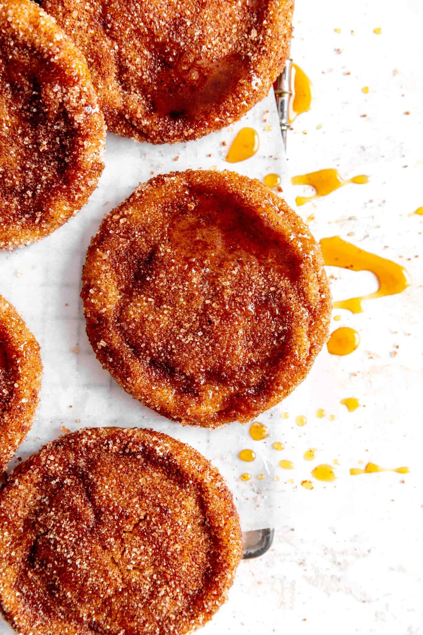 Apple cider cookies on a wire rack drizzled in caramel sauce.