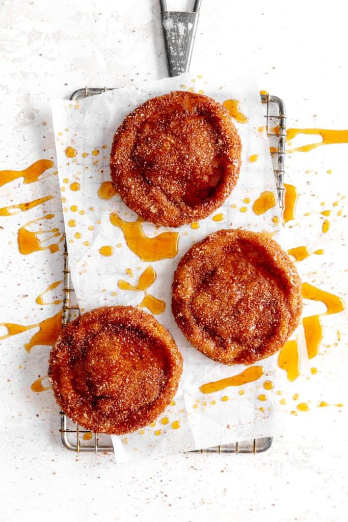 Apple cider cookies on a wire rack drizzled in caramel sauce.