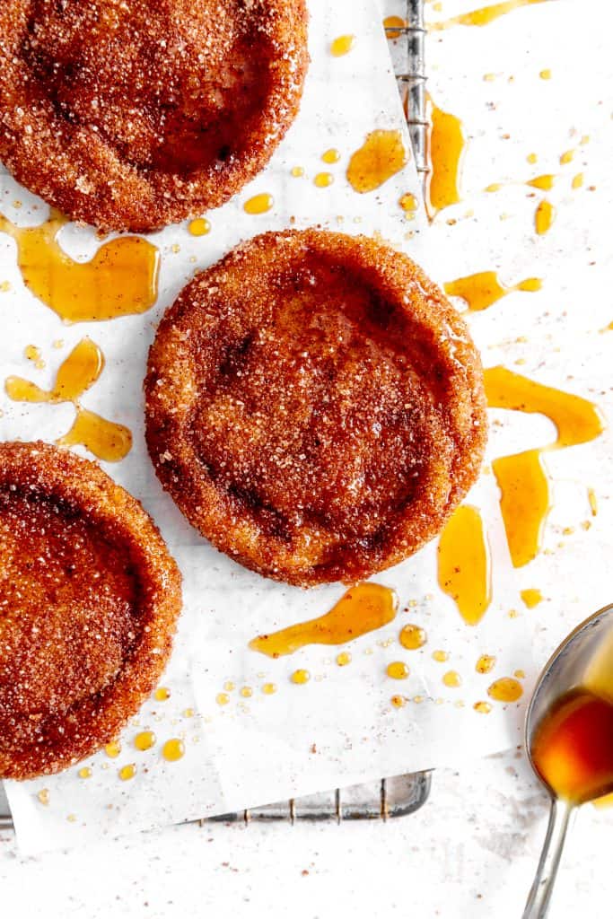 Apple cider cookie drizzled in caramel sauce and a spoon coated in caramel.