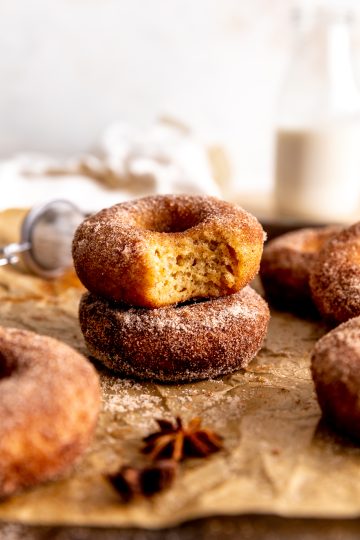 Apple cider donut with a bite taken out of it and a jug of milk.