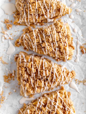 Apple cinnamon scones drizzled in glaze on a white background.