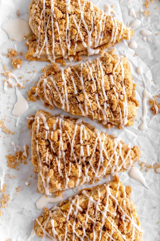 Apple cinnamon scones drizzled in glaze on a white background.