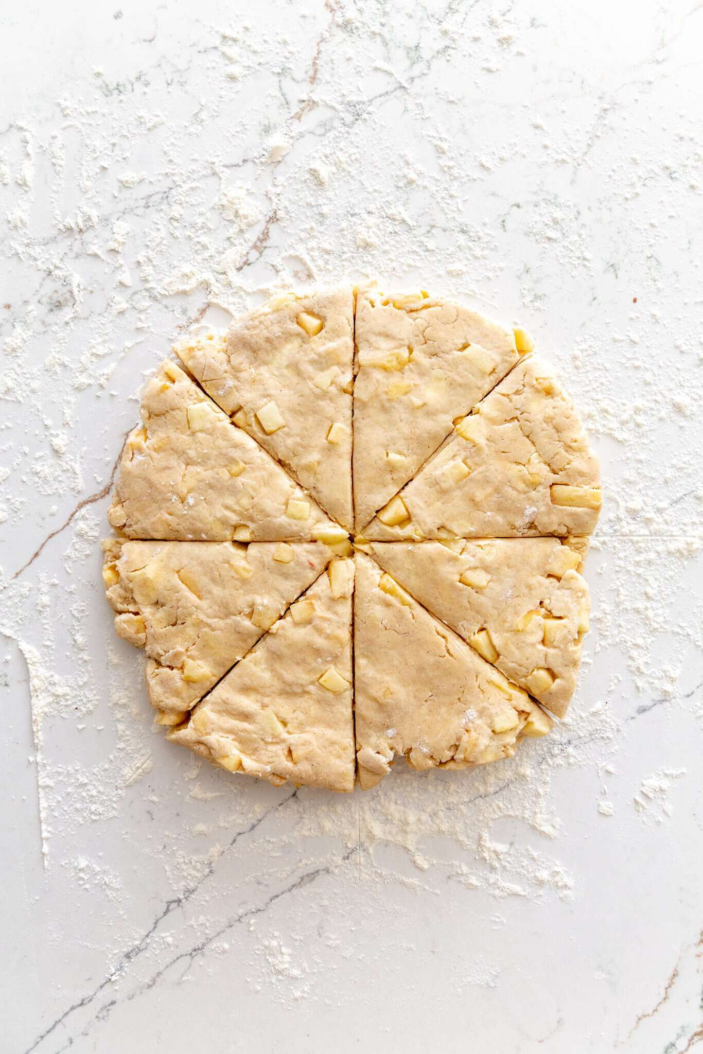 Scone dough rolled out and cut into pieces on the countertop.