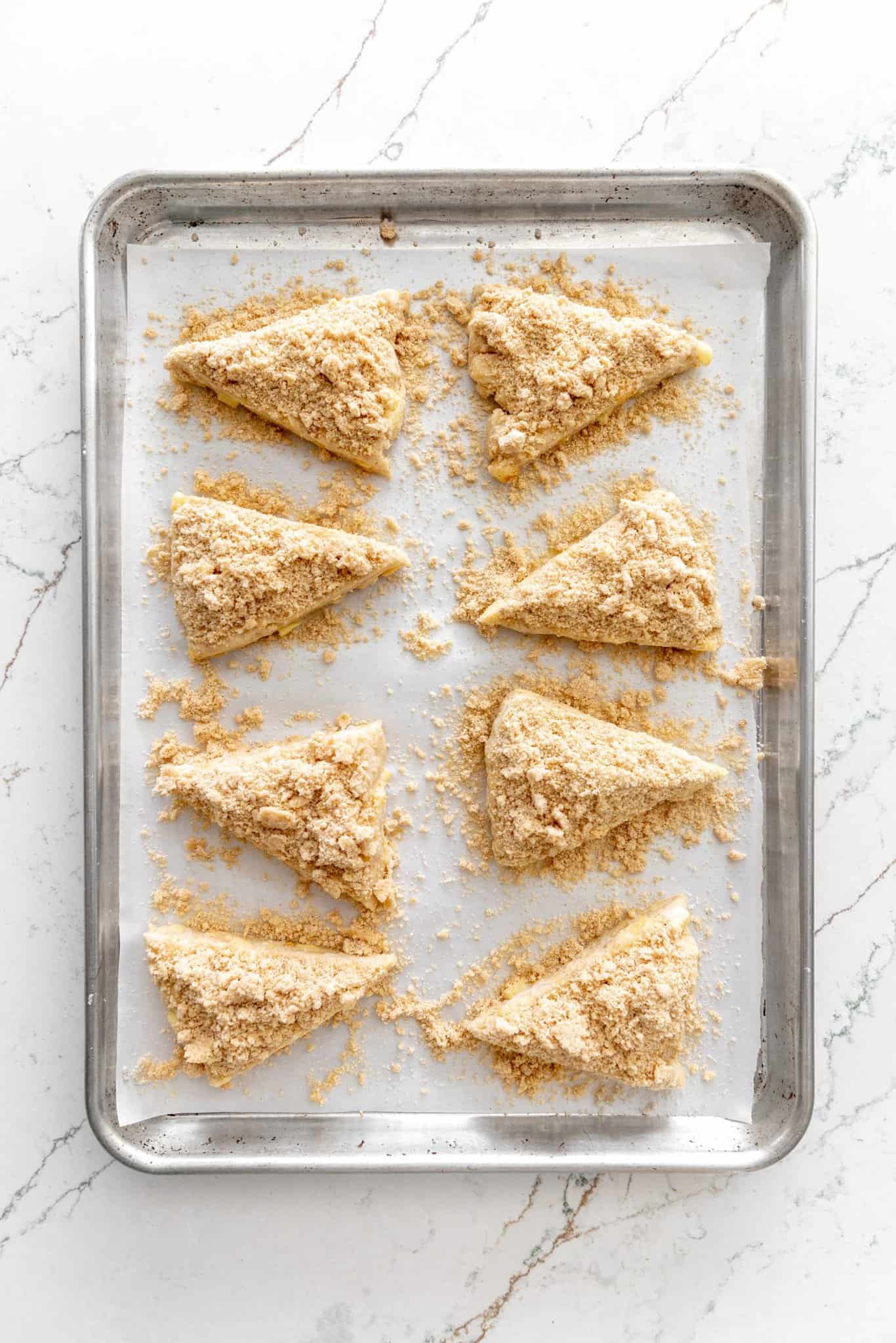 Unbaked scones covered with streusel topping on a baking sheet.