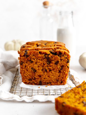 Chocolate chip pumpkin bread on a wire rack in front of a jug of milk.