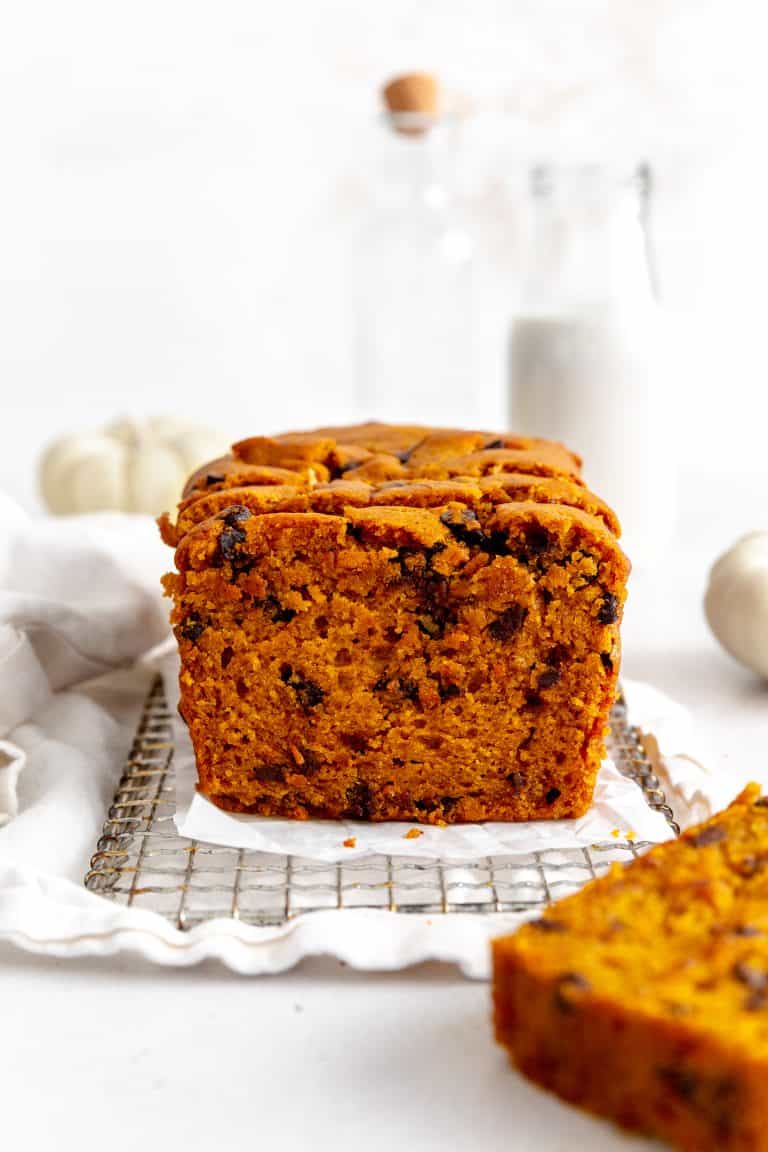 Chocolate chip pumpkin bread on a wire rack in front of a jug of milk.
