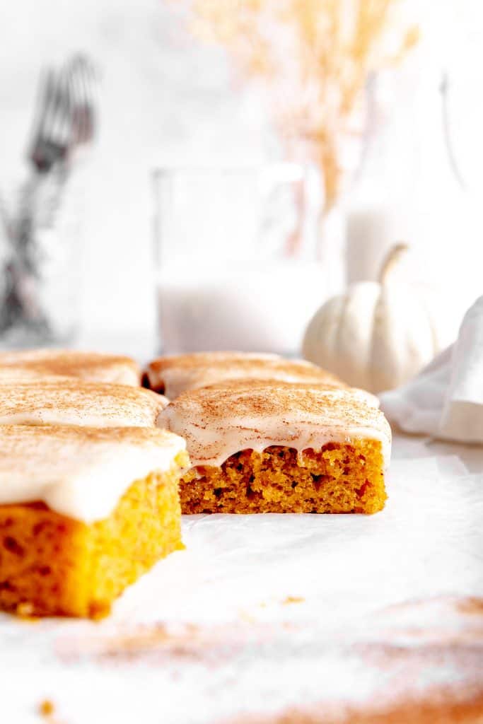 Side view of a pumpkin bar in front of a jug of milk.