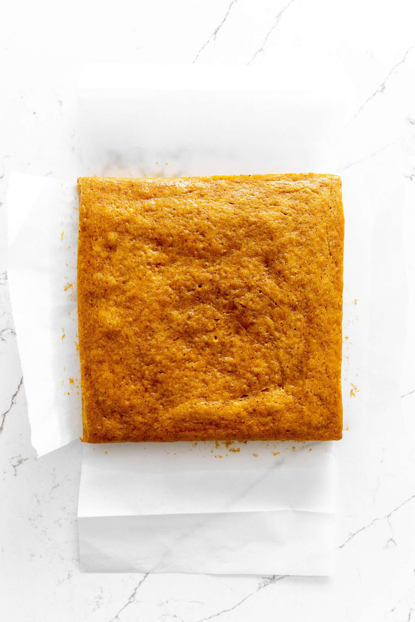 Baked, uncut pumpkin bars on parchment paper.