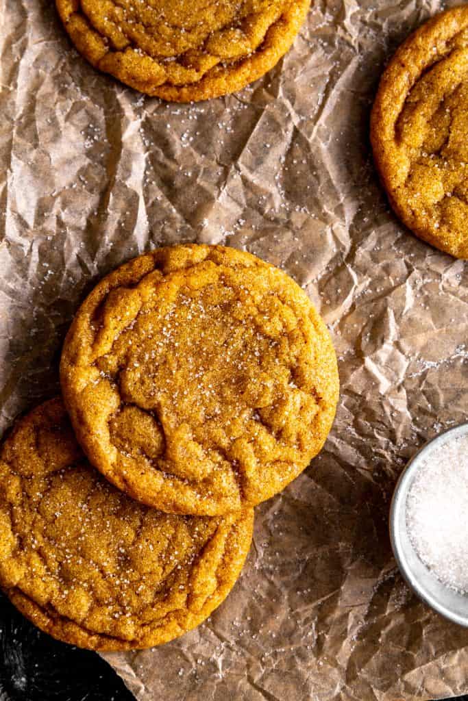 Vegan sugar cookies on a baking sheet with a cup of granulated sugar.