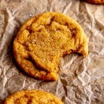 Pumpkin sugar cookie with a bite taken out of it and a jug of milk.